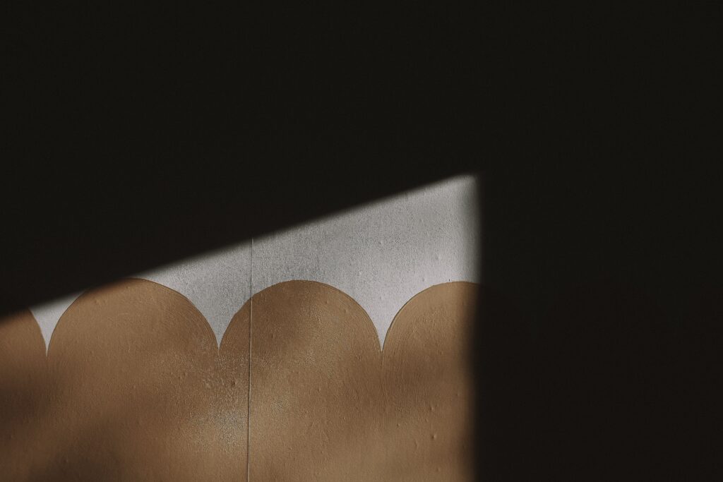 A dramatic play of light and shadow on a textured wall with a unique geometric pattern.